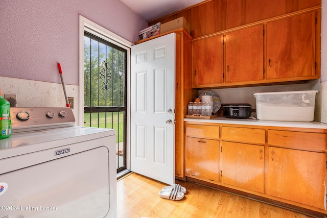 laundry area featuring washer / clothes dryer, cabinets, and light wood-type flooring