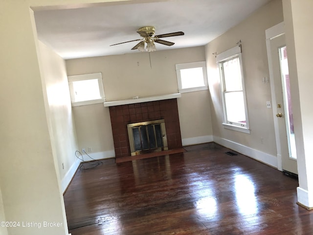 unfurnished living room featuring ceiling fan, a fireplace, and dark wood-type flooring