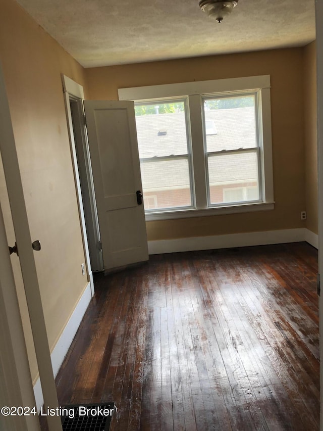 unfurnished room with dark wood-type flooring