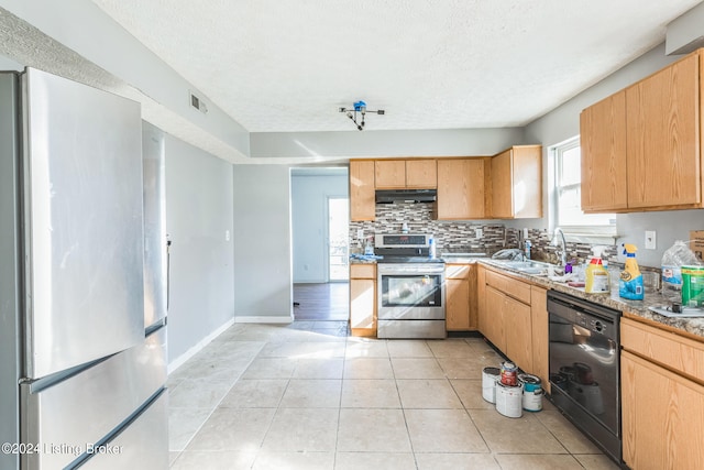 kitchen with sink, light stone countertops, light tile patterned flooring, appliances with stainless steel finishes, and a textured ceiling