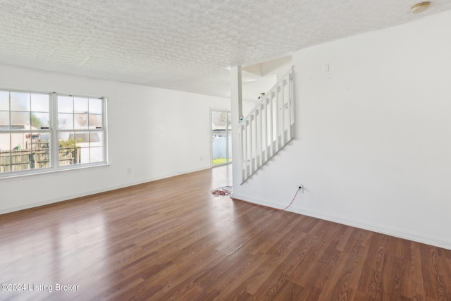 unfurnished living room with dark wood-type flooring and a textured ceiling