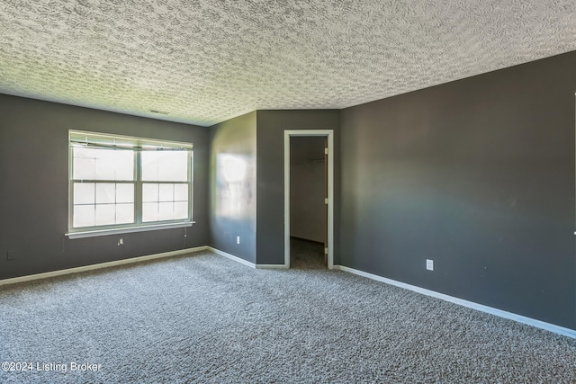 carpeted empty room with a textured ceiling