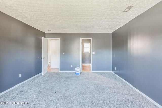 unfurnished room featuring a textured ceiling and carpet flooring