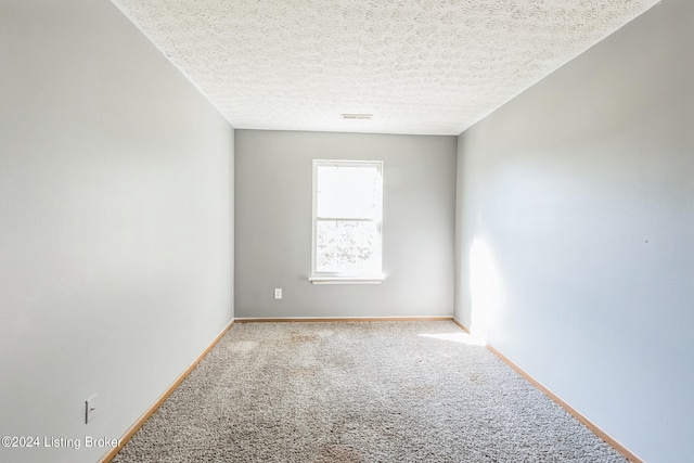 unfurnished room with a textured ceiling and light colored carpet