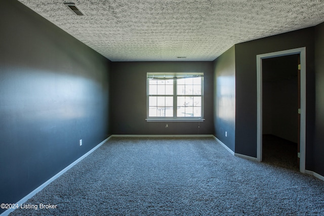 unfurnished room featuring a textured ceiling and carpet