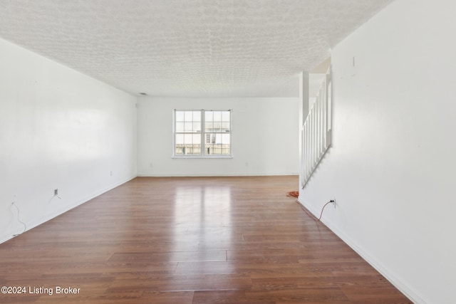 empty room with a textured ceiling and wood-type flooring