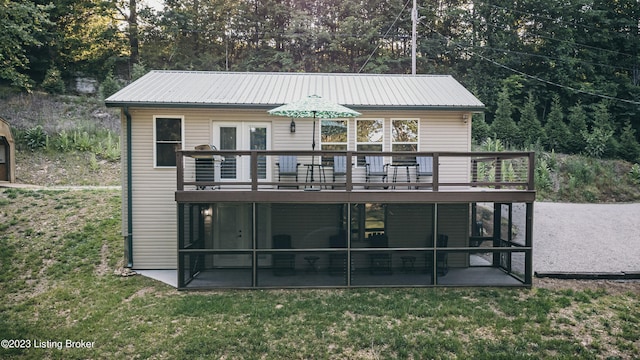 rear view of property featuring a wooden deck, a lawn, and a patio area