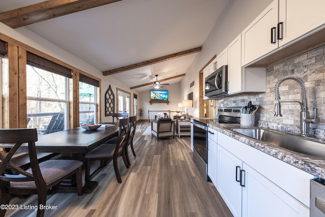 kitchen featuring white cabinets, sink, dark wood-type flooring, appliances with stainless steel finishes, and lofted ceiling with beams