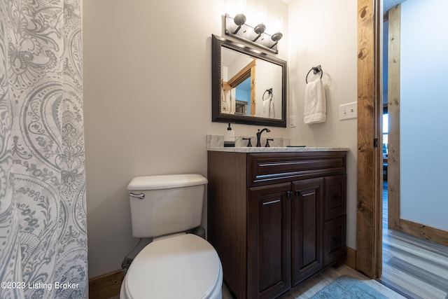 bathroom featuring wood-type flooring, vanity, and toilet