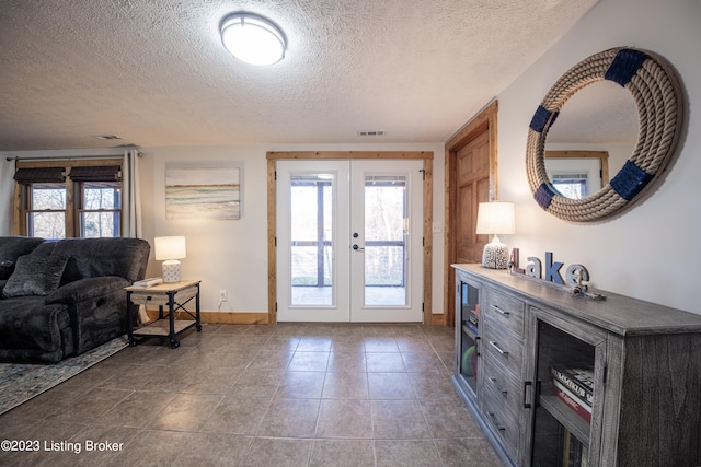 tiled entrance foyer with a textured ceiling, french doors, and a wealth of natural light