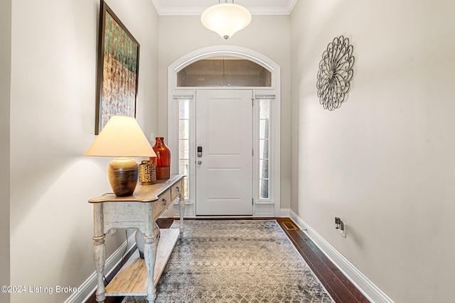 entrance foyer with ornamental molding, a wealth of natural light, and dark hardwood / wood-style flooring