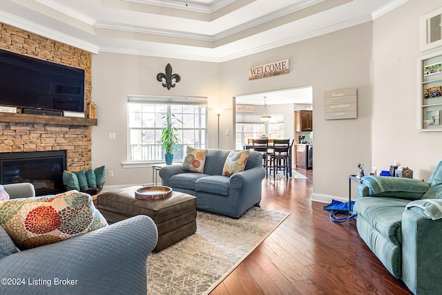 living room featuring crown molding, a stone fireplace, and dark wood-type flooring