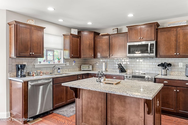 kitchen featuring appliances with stainless steel finishes, a kitchen island, sink, and dark wood-type flooring