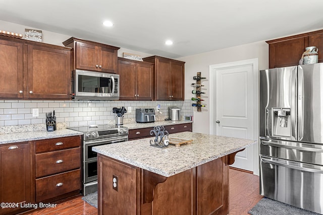 kitchen with tasteful backsplash, a kitchen island, dark wood-type flooring, stainless steel appliances, and a kitchen breakfast bar