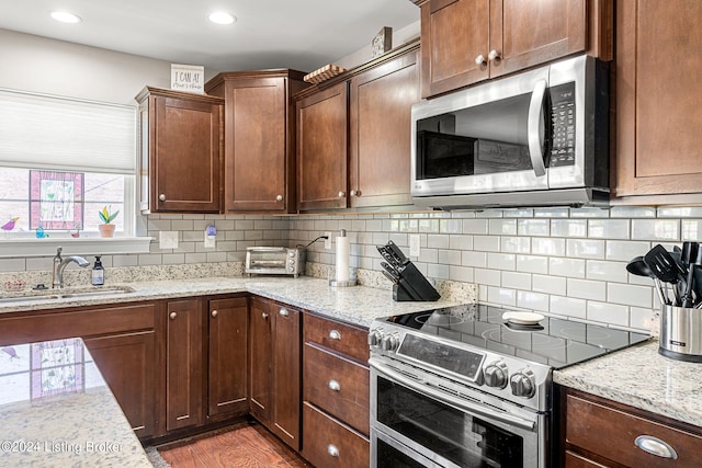 kitchen with light stone countertops, appliances with stainless steel finishes, dark wood-type flooring, and sink