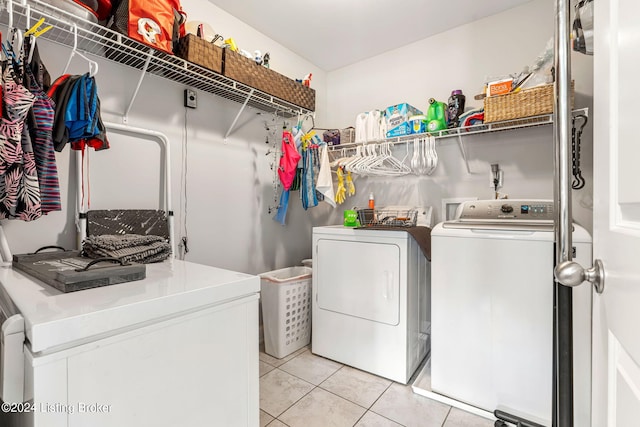 clothes washing area featuring light tile patterned floors and washer and clothes dryer