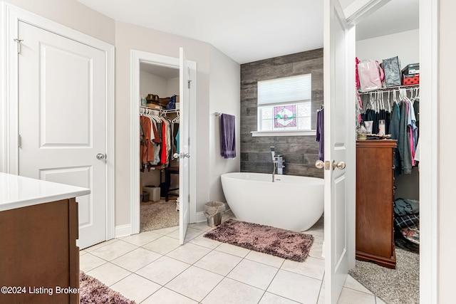 bathroom with vanity, tile walls, tile patterned flooring, and a washtub