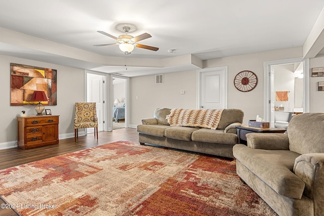 living room with ceiling fan and dark wood-type flooring