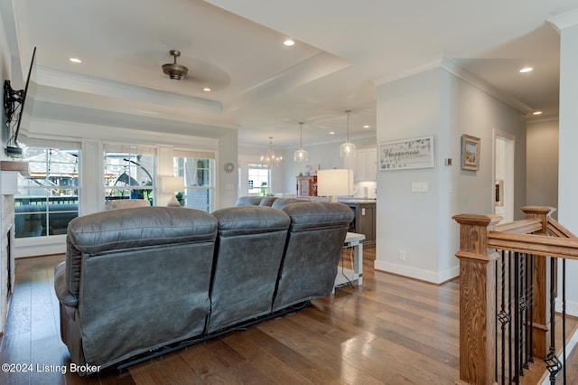 living room featuring hardwood / wood-style flooring, ceiling fan, a raised ceiling, and ornamental molding