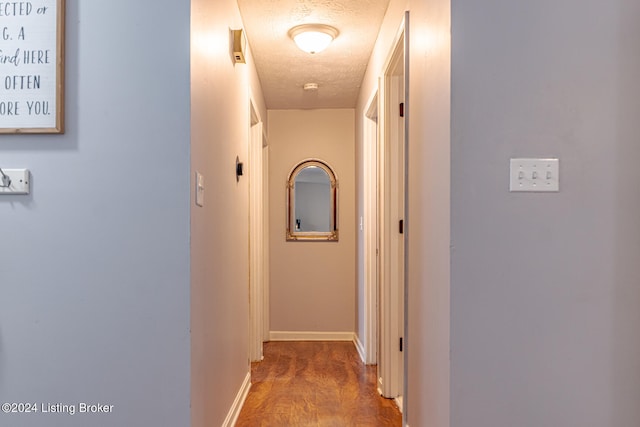 corridor with a textured ceiling and hardwood / wood-style flooring