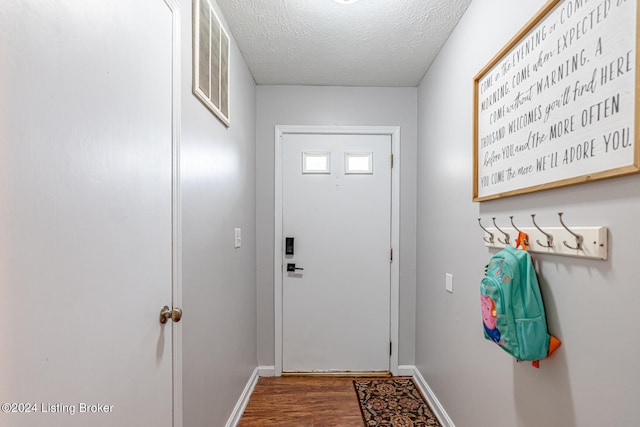 doorway with a textured ceiling and dark hardwood / wood-style flooring