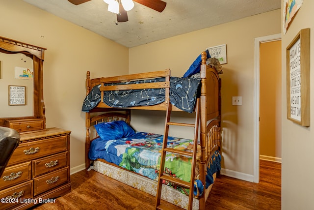 bedroom with a textured ceiling, ceiling fan, and dark wood-type flooring