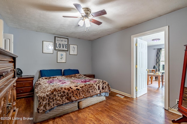 bedroom featuring a textured ceiling, ceiling fan, and dark wood-type flooring