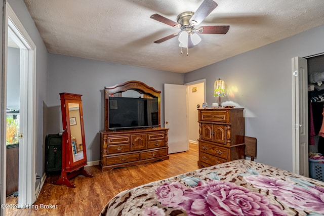 bedroom with light wood-type flooring, a textured ceiling, and ceiling fan