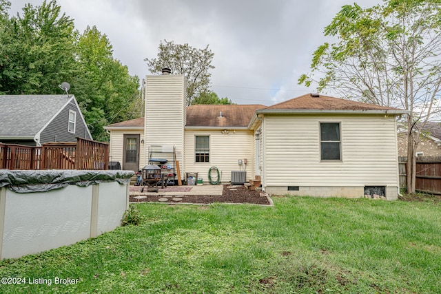 back of property featuring a lawn, a swimming pool side deck, central AC unit, and a patio area