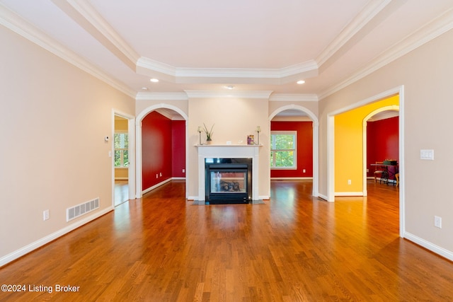 unfurnished living room with hardwood / wood-style floors, ornamental molding, and a tray ceiling