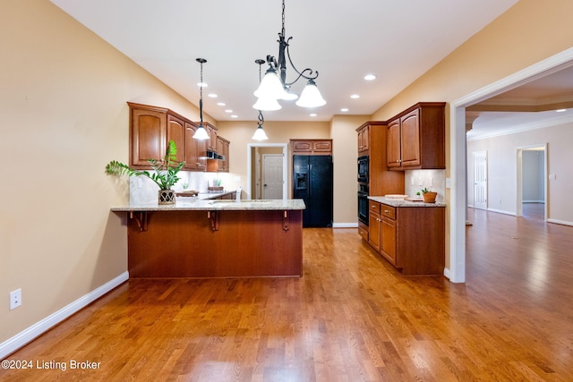 kitchen with hardwood / wood-style floors, an inviting chandelier, black appliances, crown molding, and kitchen peninsula