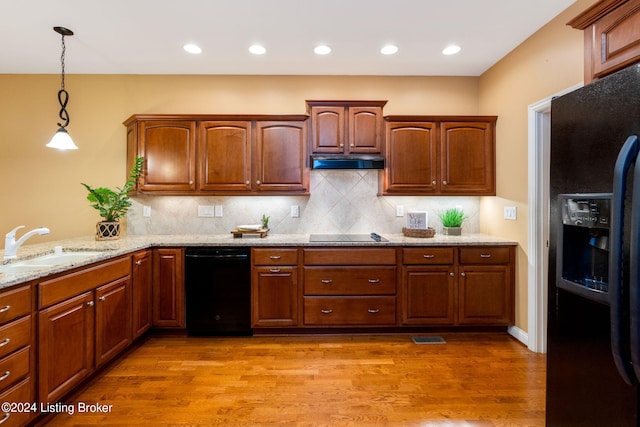 kitchen with black appliances, hanging light fixtures, sink, hardwood / wood-style flooring, and tasteful backsplash