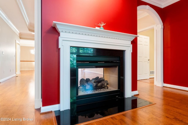 interior details with a multi sided fireplace, wood-type flooring, and ornamental molding