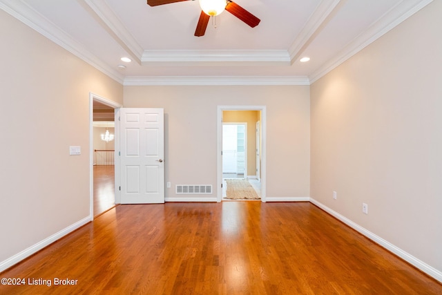 unfurnished room with ceiling fan, a raised ceiling, wood-type flooring, and crown molding