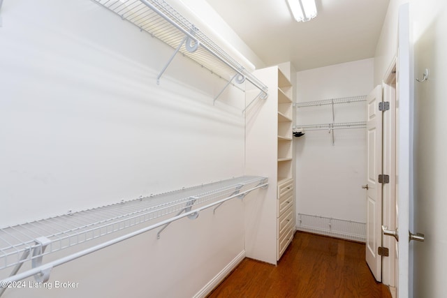 walk in closet with dark wood-type flooring