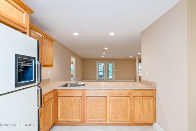 kitchen with sink, white refrigerator with ice dispenser, kitchen peninsula, and light brown cabinetry