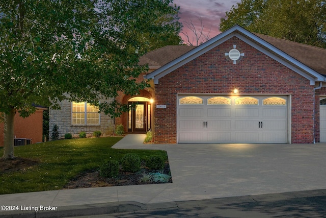 view of front of home with central AC, a yard, and a garage