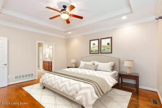 bedroom featuring a raised ceiling, crown molding, hardwood / wood-style floors, and ceiling fan