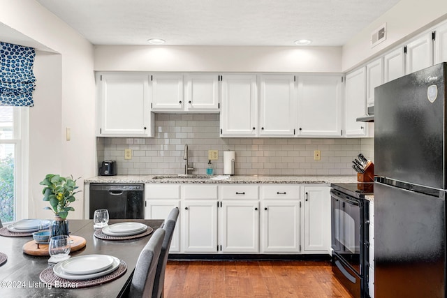 kitchen with light stone counters, sink, dark wood-type flooring, white cabinetry, and black appliances