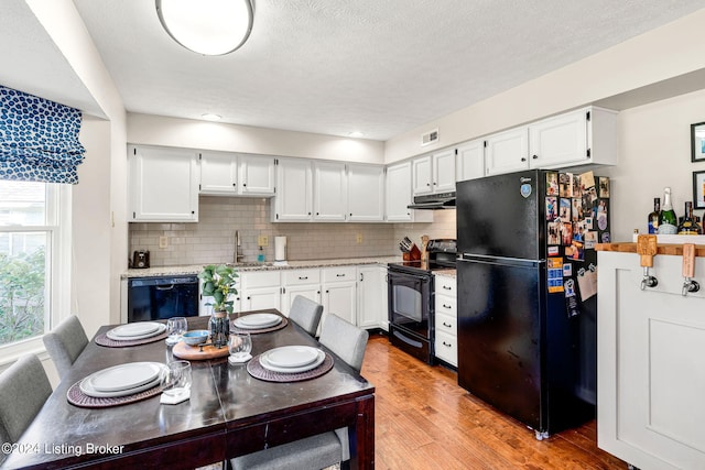 kitchen with black appliances, decorative backsplash, light hardwood / wood-style flooring, and white cabinets