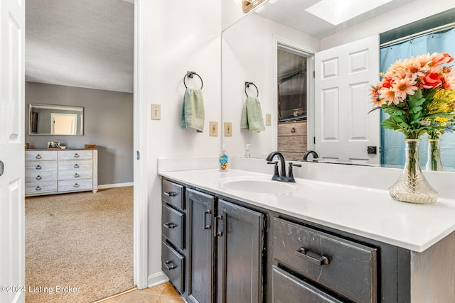 bathroom with tile patterned flooring, a textured ceiling, a skylight, and vanity