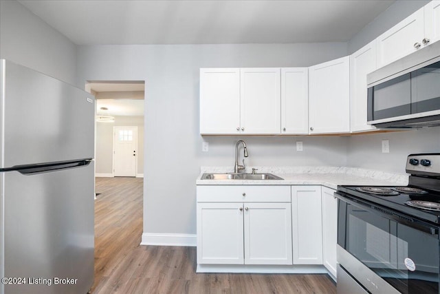 kitchen with white cabinetry, sink, light hardwood / wood-style floors, and appliances with stainless steel finishes