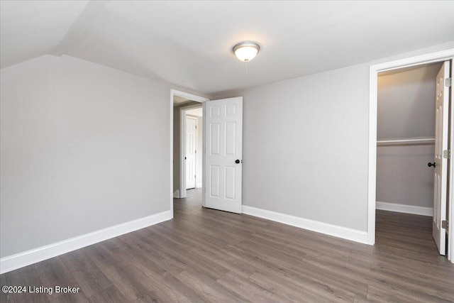 unfurnished bedroom with dark hardwood / wood-style floors, a closet, and lofted ceiling