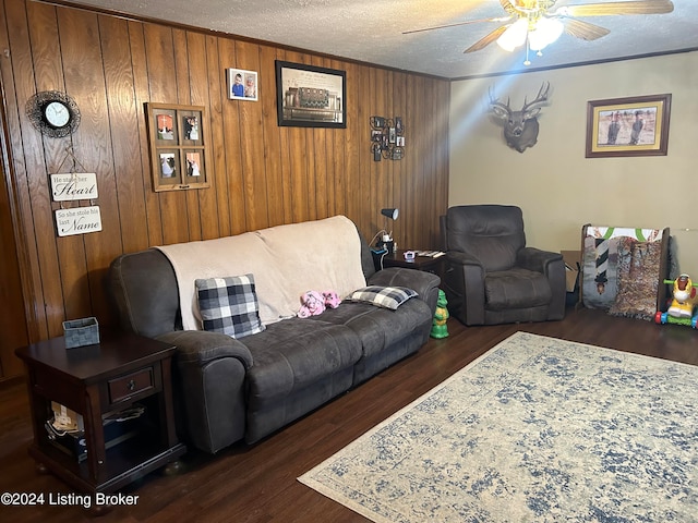 living room with ceiling fan, dark hardwood / wood-style flooring, a textured ceiling, and wooden walls