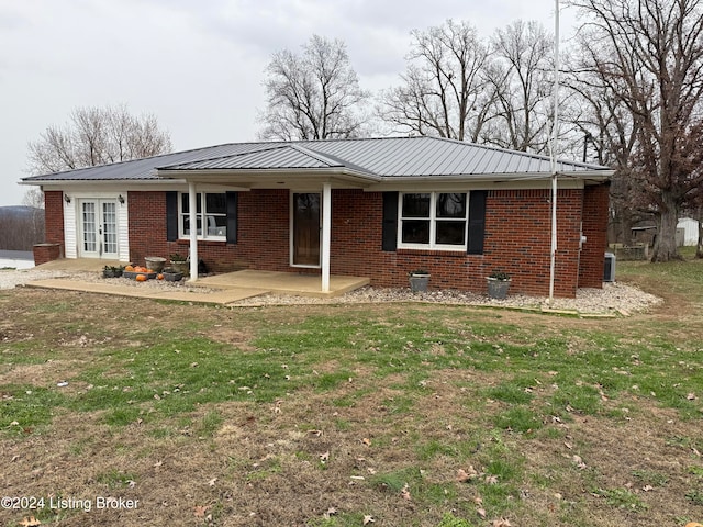 single story home with french doors, a front lawn, and a patio