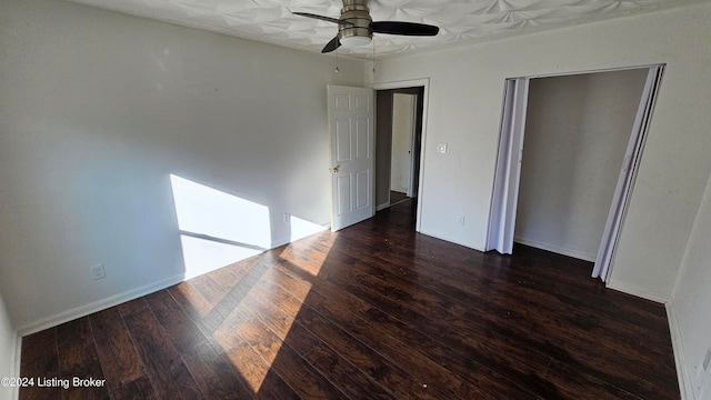 unfurnished bedroom with dark wood-type flooring, a closet, and ceiling fan