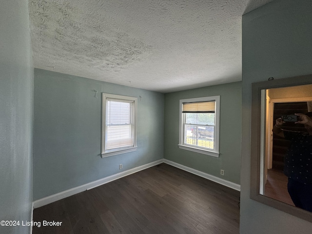 empty room featuring a textured ceiling and dark wood-type flooring