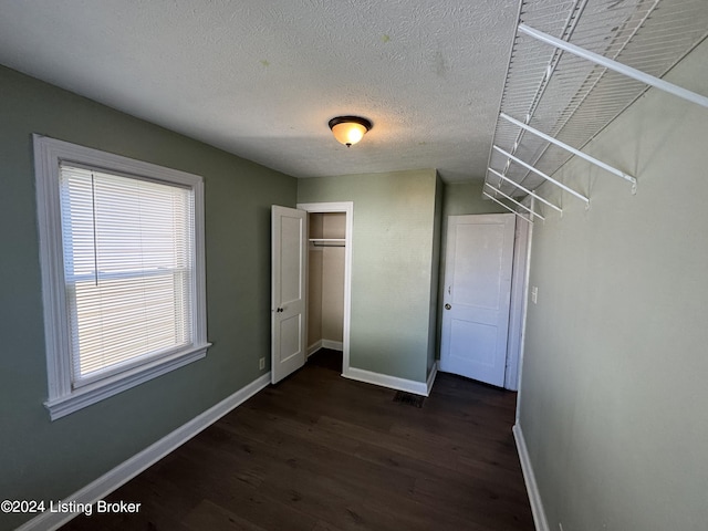 unfurnished bedroom featuring a textured ceiling, dark wood-type flooring, and a closet