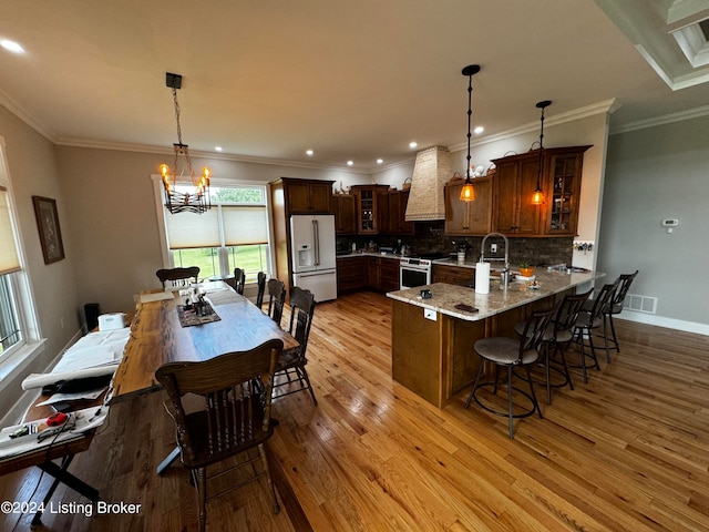 kitchen featuring white fridge with ice dispenser, hanging light fixtures, kitchen peninsula, electric range, and light wood-type flooring