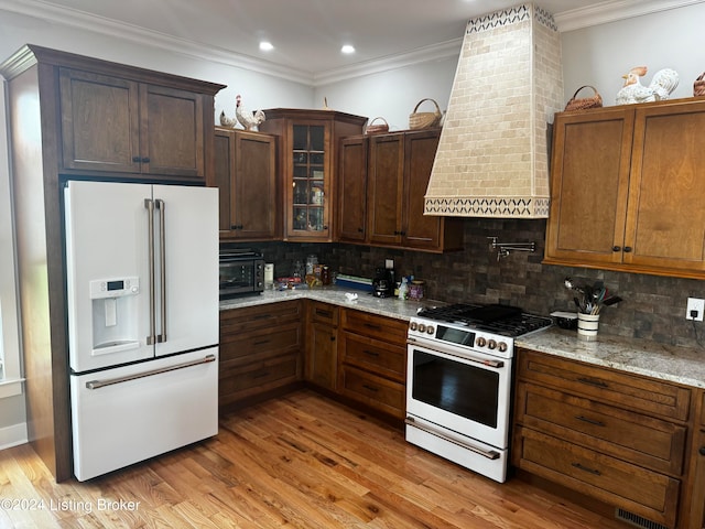 kitchen featuring premium appliances, light stone countertops, and light hardwood / wood-style flooring